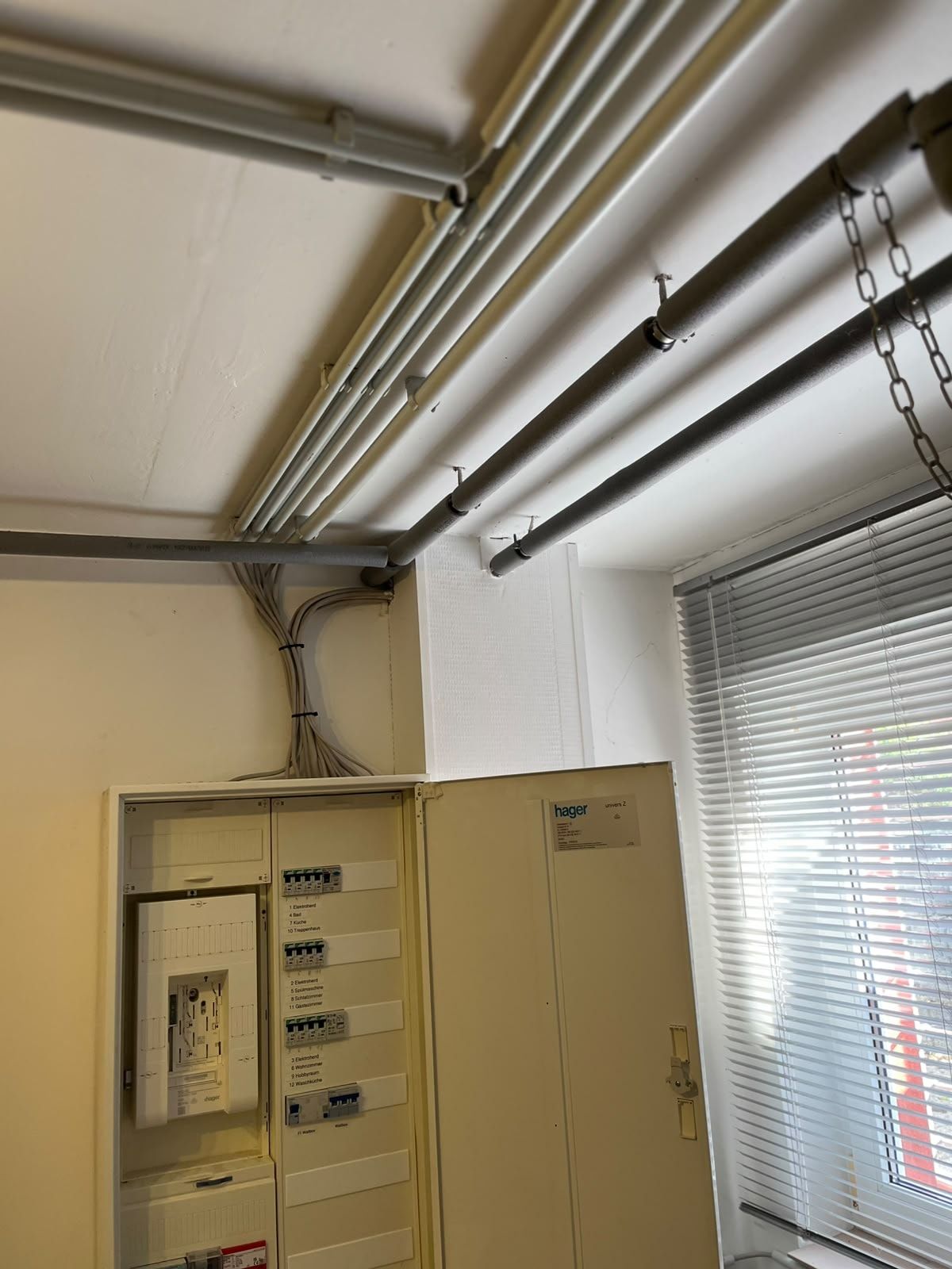 Zählerschrank im Hausanschlussraum, darüber sauber gebündelte Zuleitungen aus der Decke